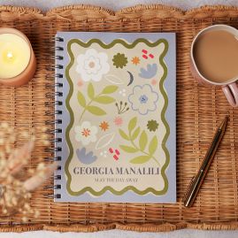 Diary in the centre of a seagrass, scalloped tray, with a cup of tea and gold pen.