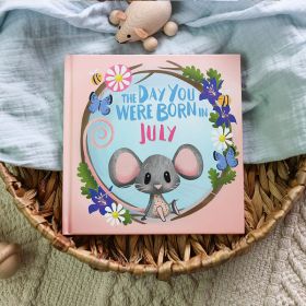 The book cover for Day You Were Born In July. A playful, illustrated mouse sat down surrounded by daisies, delphiniums, bees and butterflies.